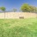 a grassy area with a stone wall and trees in the background