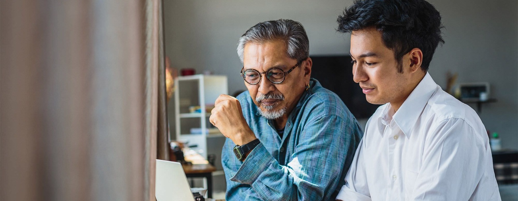 Older man and younger man looking at a laptop